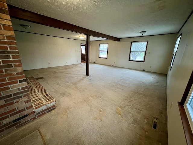 basement featuring visible vents, light carpet, and a textured ceiling