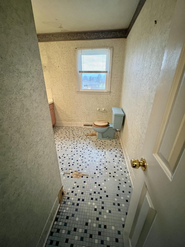 bathroom featuring baseboards, toilet, and a textured wall