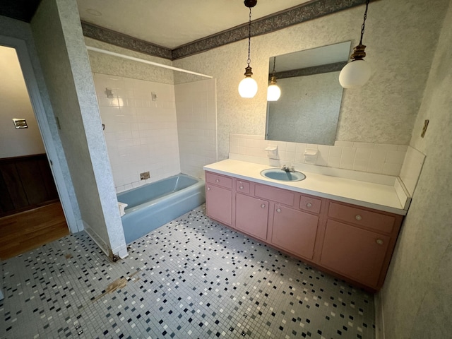 full bath with a wainscoted wall, wallpapered walls, vanity, and bathtub / shower combination