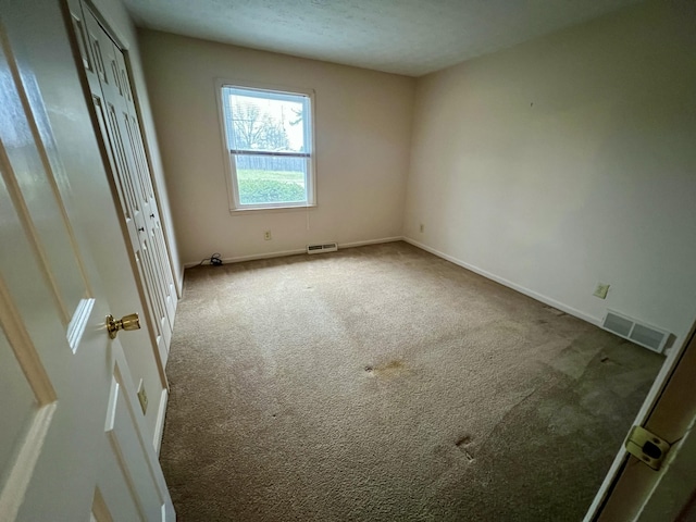 unfurnished bedroom with baseboards, visible vents, carpet floors, and a textured ceiling