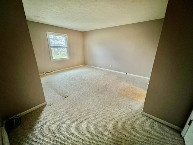 spare room with visible vents, baseboards, and a textured ceiling