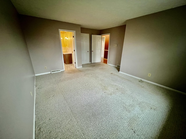 unfurnished bedroom featuring visible vents, baseboards, carpet, and ensuite bath