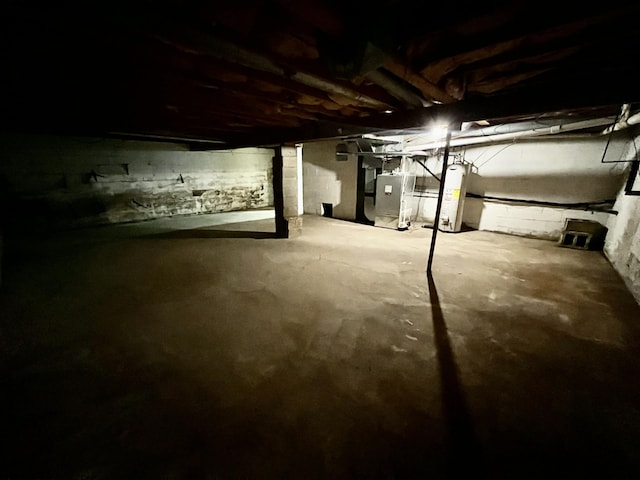 unfinished basement featuring gas water heater and heating unit