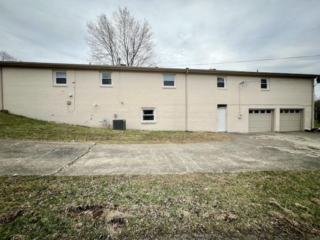 view of side of home featuring brick siding, central air condition unit, and a garage