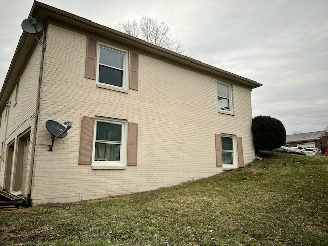 view of home's exterior with brick siding and a lawn