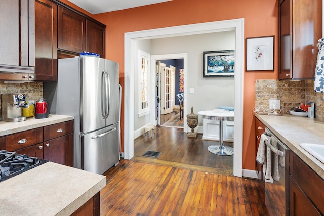 kitchen featuring appliances with stainless steel finishes, backsplash, and dark hardwood / wood-style flooring