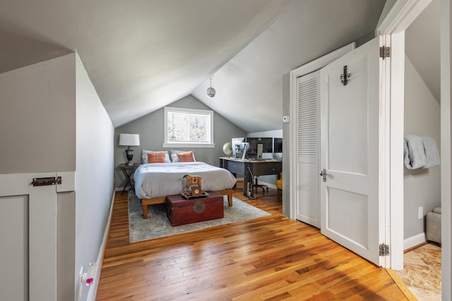 bedroom with light wood-type flooring and lofted ceiling