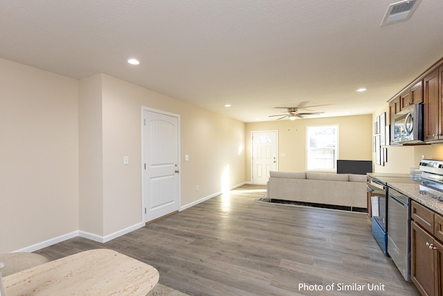 kitchen with ceiling fan, hardwood / wood-style flooring, stainless steel appliances, and light stone counters