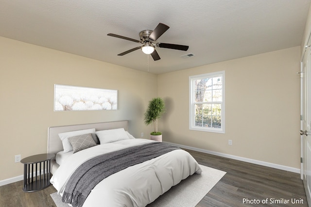 bedroom with a textured ceiling, ceiling fan, and dark hardwood / wood-style flooring