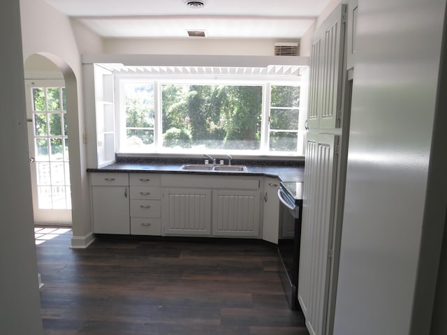 kitchen featuring a sink, visible vents, dark countertops, electric range, and stainless steel refrigerator
