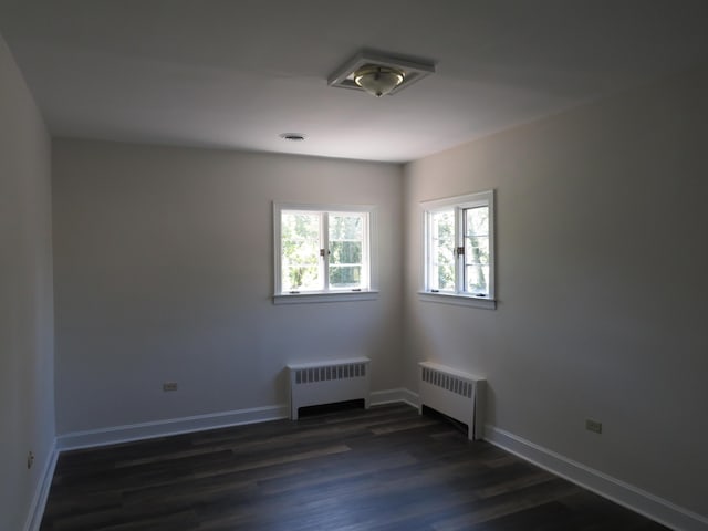 spare room with visible vents, baseboards, dark wood-style floors, and radiator