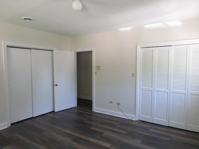 unfurnished bedroom featuring dark wood-style flooring, baseboards, and visible vents