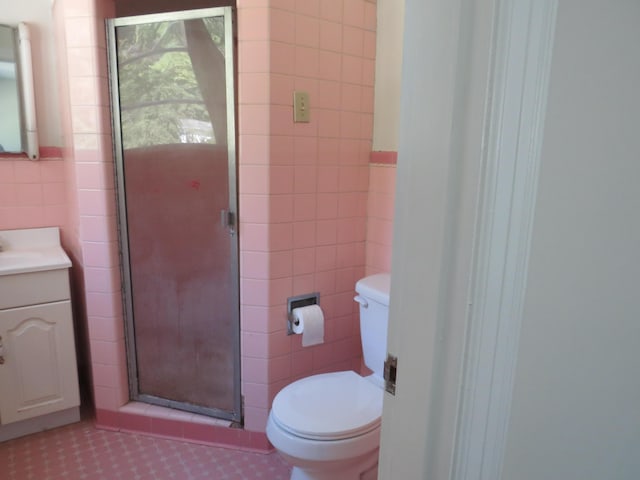 full bathroom featuring tile walls, a shower stall, vanity, tile patterned floors, and toilet