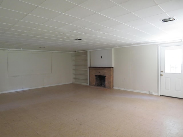 unfurnished living room featuring built in shelves, visible vents, baseboards, and a fireplace