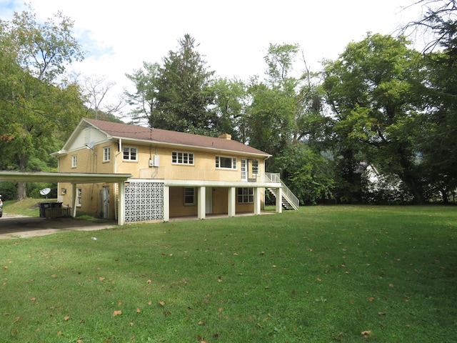 rear view of property with a lawn, a chimney, stairs, and a carport