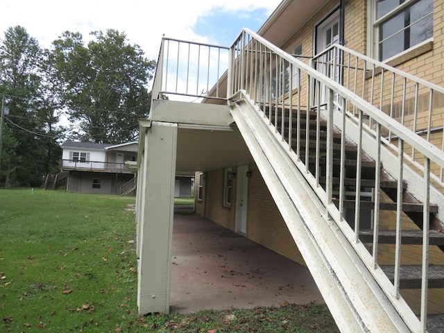 view of side of home with a lawn, stairway, and brick siding