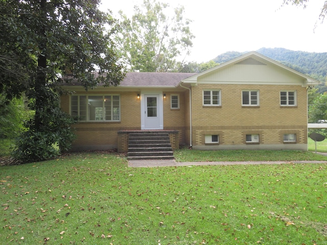 view of front of property with a front yard, a mountain view, and brick siding