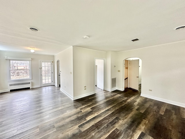 unfurnished living room with visible vents, radiator, arched walkways, and dark wood-type flooring