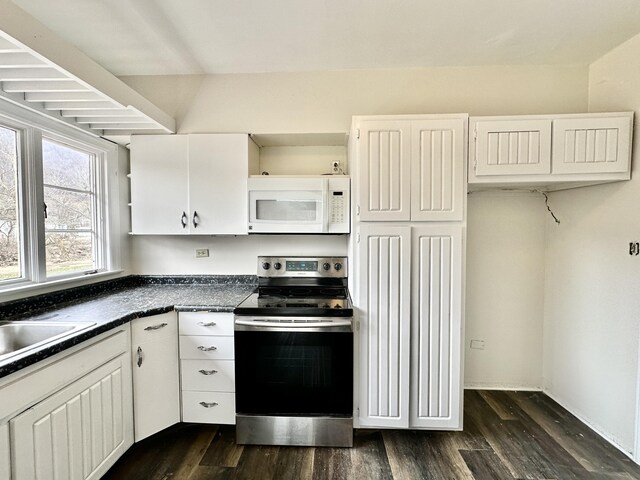 kitchen featuring white microwave, dark countertops, white cabinetry, stainless steel range with electric stovetop, and dark wood-type flooring