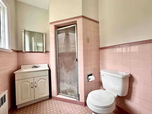 full bathroom with a stall shower, tile walls, radiator heating unit, and wainscoting