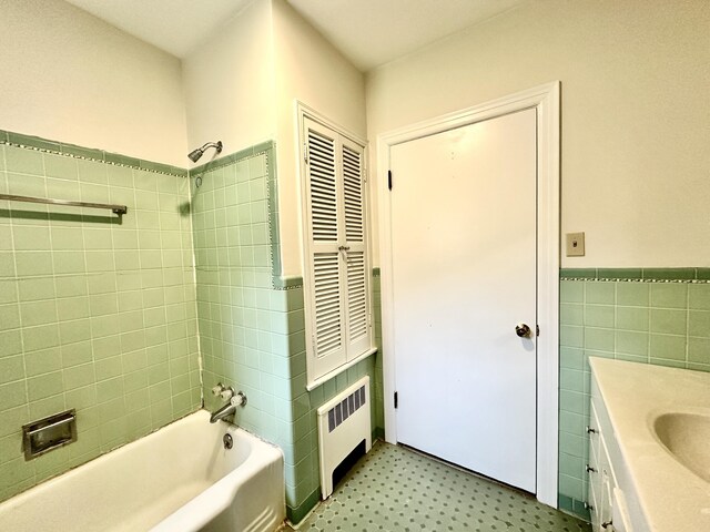 bathroom with tile walls, vanity, tile patterned floors, radiator heating unit, and shower / washtub combination