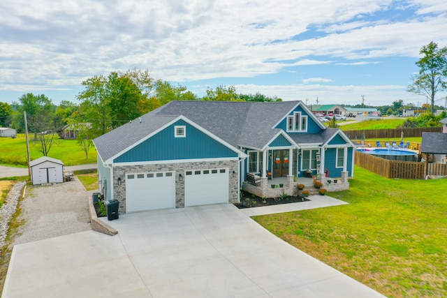 craftsman house featuring a shed, a porch, a front yard, and a garage