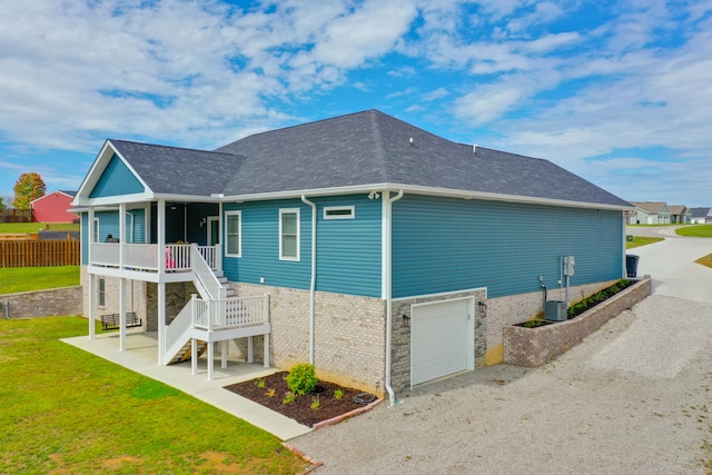 view of side of home featuring covered porch, cooling unit, a garage, and a yard