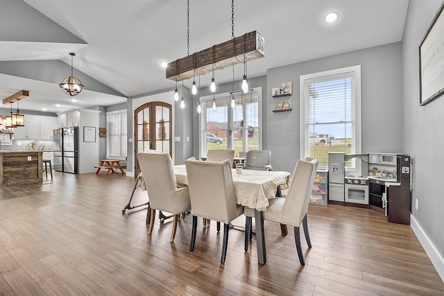 dining space featuring hardwood / wood-style floors, lofted ceiling, and a chandelier