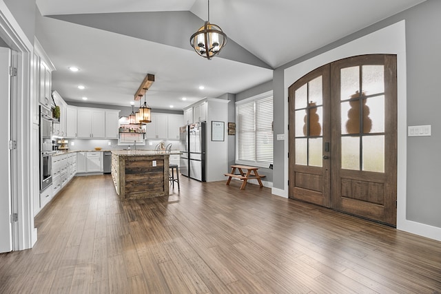 kitchen featuring appliances with stainless steel finishes, french doors, pendant lighting, a kitchen island, and lofted ceiling