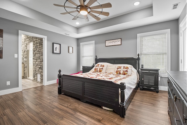 bedroom featuring ceiling fan, ensuite bathroom, and dark wood-type flooring