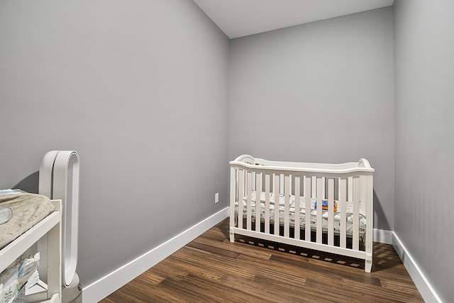 bedroom featuring dark hardwood / wood-style floors and a nursery area