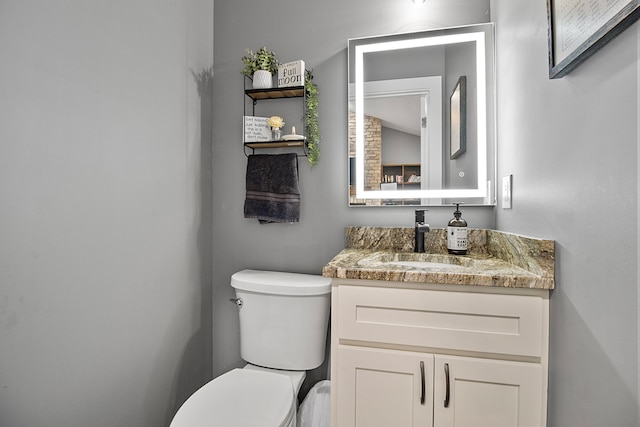 bathroom featuring vanity, toilet, and vaulted ceiling