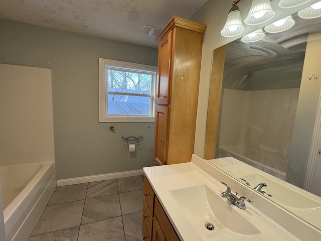 bathroom with tile patterned flooring, vanity, a bathing tub, and a textured ceiling