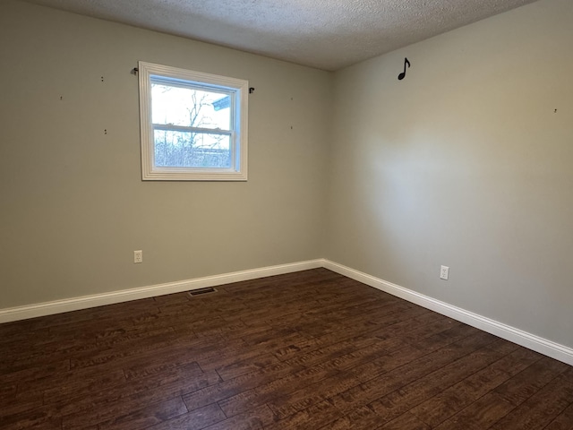 empty room with a textured ceiling and dark wood-type flooring