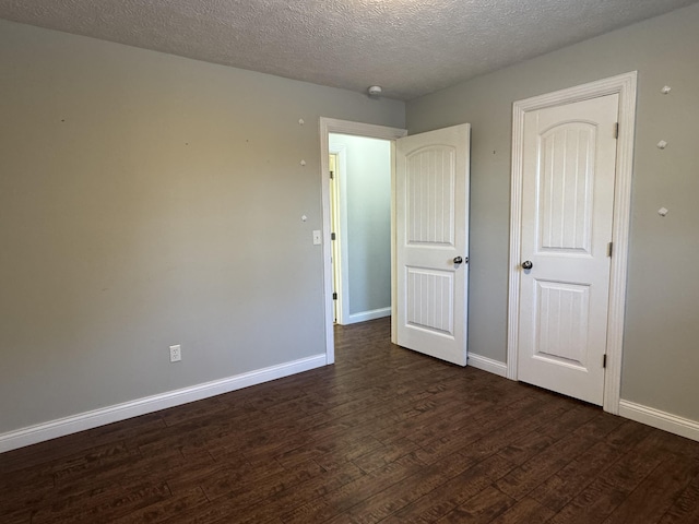 unfurnished bedroom featuring a textured ceiling and dark wood-type flooring