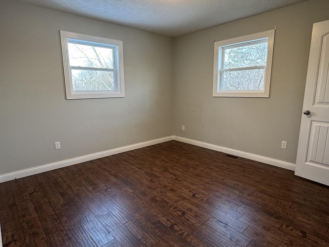 unfurnished room featuring a textured ceiling, dark hardwood / wood-style floors, and plenty of natural light