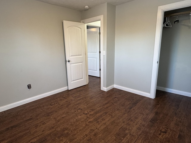 unfurnished bedroom with a closet and dark wood-type flooring