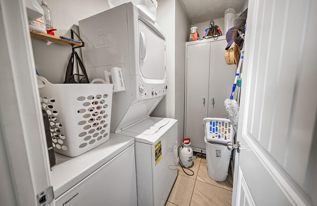 laundry room with light tile patterned floors, a textured ceiling, and stacked washer / drying machine