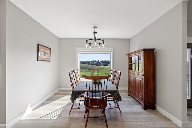 dining space with light hardwood / wood-style floors and a notable chandelier