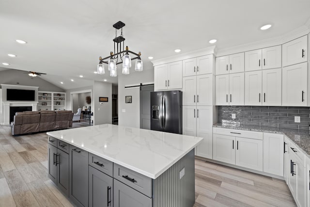 kitchen featuring light hardwood / wood-style flooring, white cabinetry, stainless steel refrigerator with ice dispenser, ceiling fan with notable chandelier, and a barn door