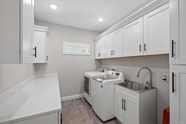 laundry area featuring sink, washing machine and clothes dryer, and cabinets