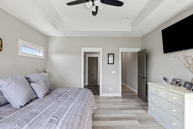 bedroom featuring a raised ceiling, light hardwood / wood-style floors, and ceiling fan