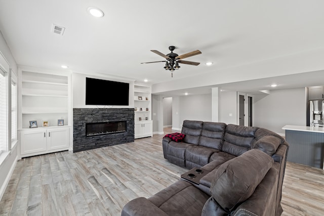 living room with a fireplace, built in features, plenty of natural light, and light hardwood / wood-style flooring