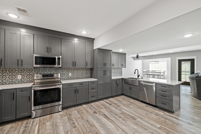 kitchen with sink, kitchen peninsula, light hardwood / wood-style flooring, gray cabinets, and appliances with stainless steel finishes