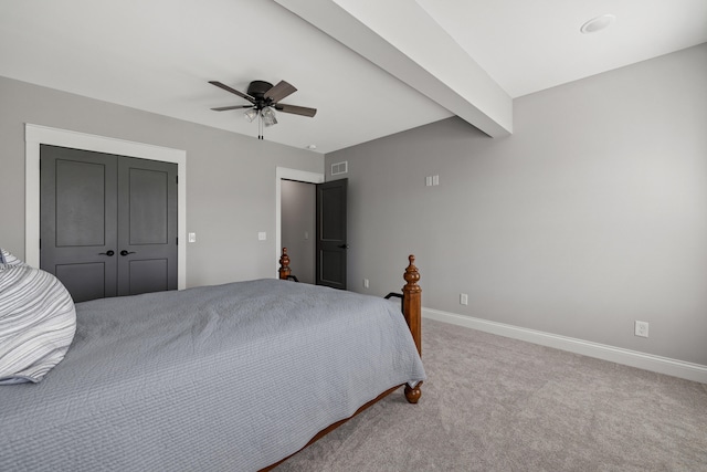 carpeted bedroom with beamed ceiling, ceiling fan, and a closet