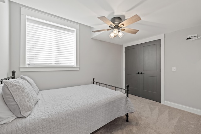 carpeted bedroom featuring ceiling fan and a closet