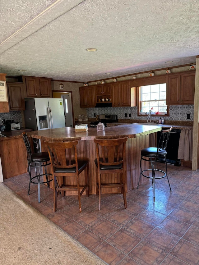 kitchen with black appliances, sink, a textured ceiling, a kitchen island, and a kitchen bar