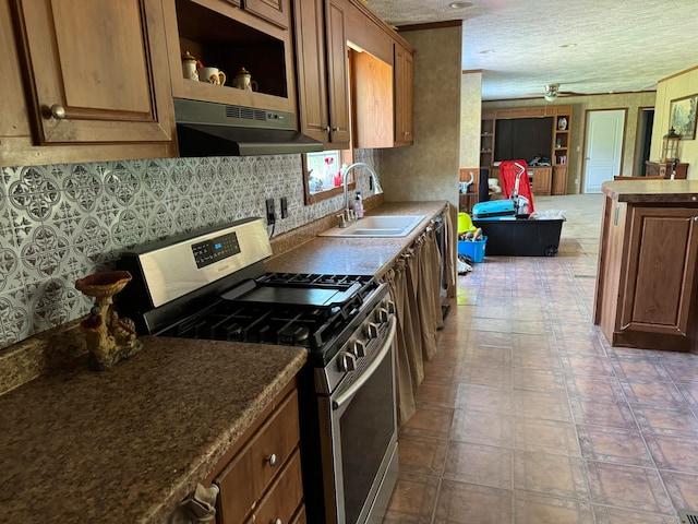 kitchen with exhaust hood, stainless steel range with gas cooktop, sink, ceiling fan, and a textured ceiling