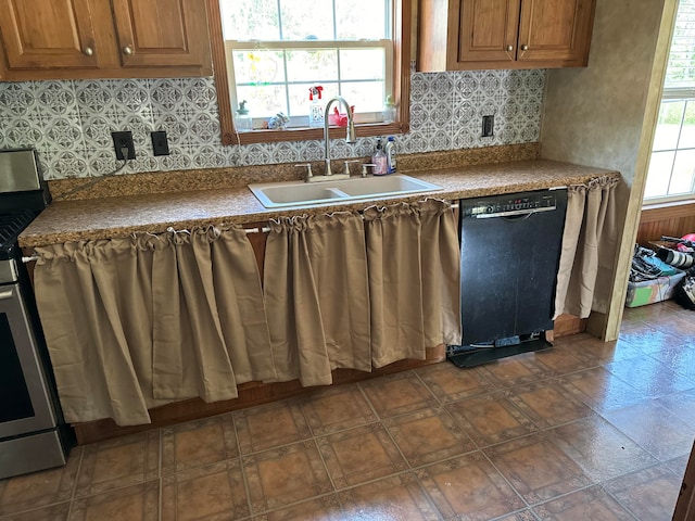 kitchen featuring tasteful backsplash, dishwasher, sink, and stainless steel range oven