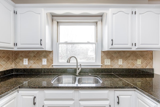 kitchen with tasteful backsplash, sink, white cabinets, and dark stone counters